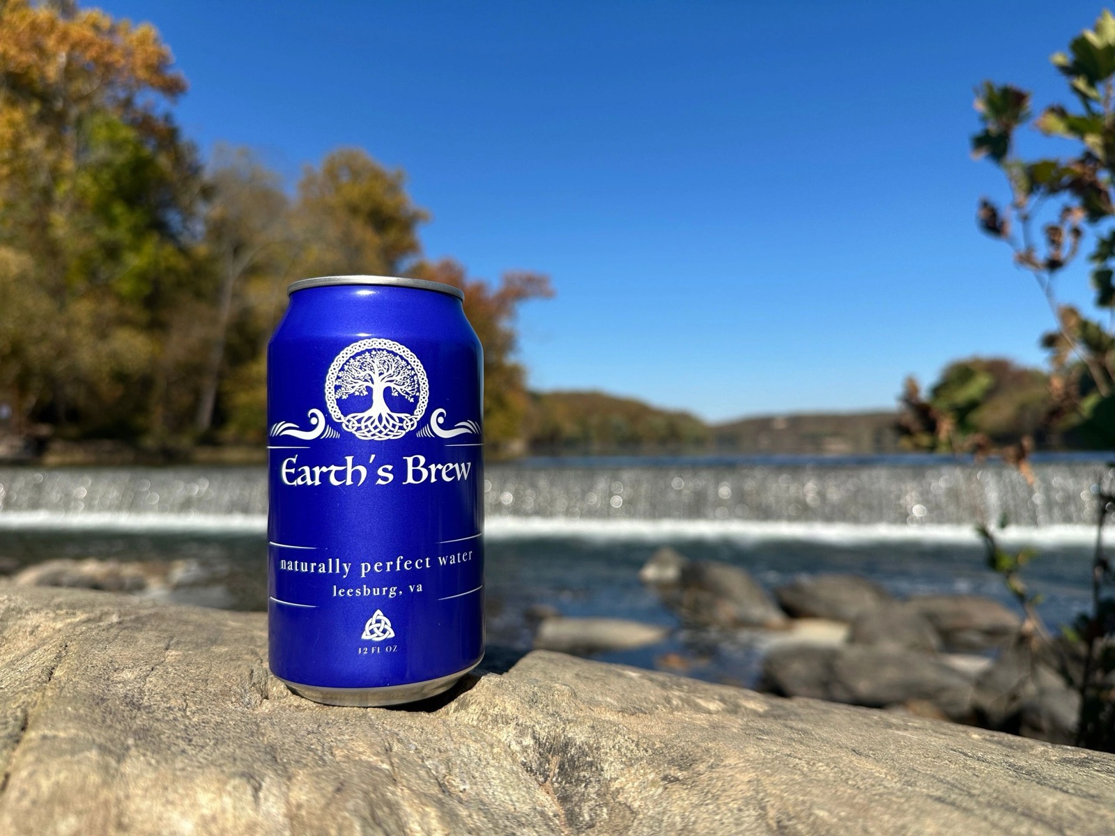 An Earth's Brew can on limestone beside a Virginia river weir at golden hour